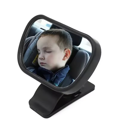 Child in a car seat reflected in a black car mirror on a white background