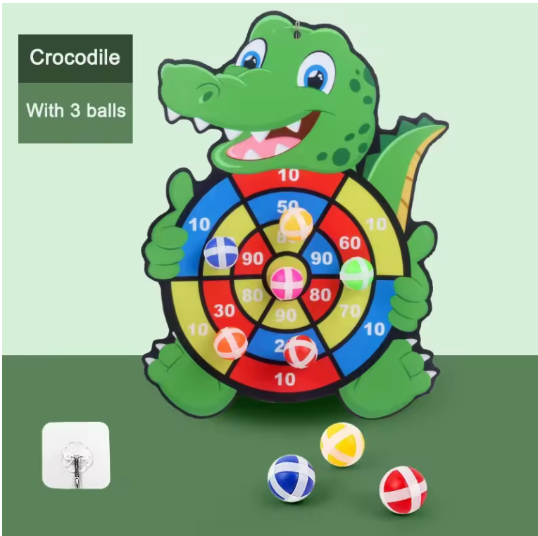 Crocodile-shaped dartboard with three balls on a green background